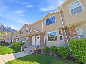 View of front facade with stucco siding, a front lawn, stone siding, a mountain view, and a residential view