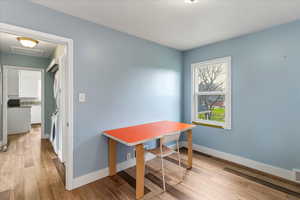 Office with stacked washer and clothes dryer and light wood finished floors