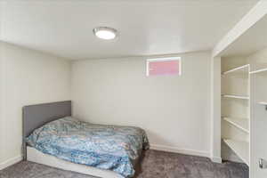 Bedroom featuring dark carpet and baseboards
