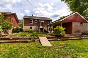 Back of house featuring a yard, a chimney, and a patio area