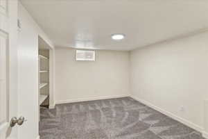 Finished below grade area featuring baseboards and dark colored carpet