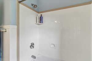 Bathroom featuring washtub / shower combination and wainscoting