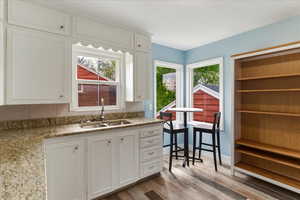 Kitchen featuring light stone counters, light wood-type flooring, white cabinets, and plenty of natural light