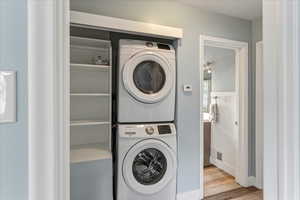 Laundry area featuring stacked washer and dryer and light wood-type flooring