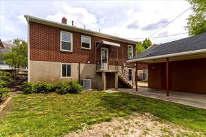 Back of property with a yard, a chimney, and brick siding