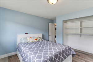 Bedroom with a closet, stacked washer and clothes dryer, and light wood-type flooring