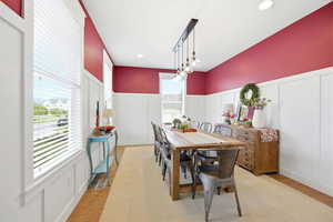 Dining area with a decorative wall, wainscoting, light wood-type flooring, and recessed lighting