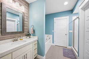 Full bath featuring a shower stall, a garden tub, and vanity