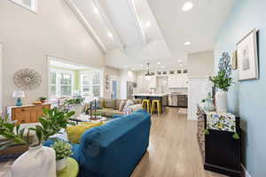 Living room featuring light wood-style flooring, vaulted ceiling, and recessed lighting