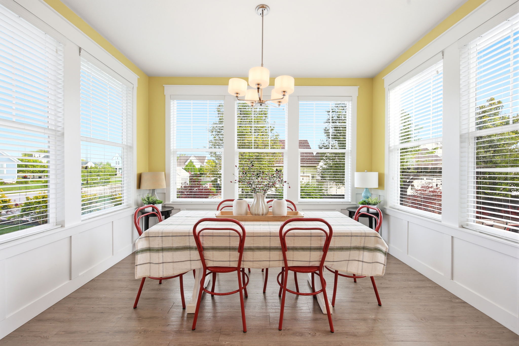 Dining area with a decorative wall, wainscoting, suspended lighting, and wood finished floors