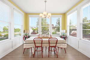Dining area with a decorative wall, wainscoting, suspended lighting, and wood finished floors
