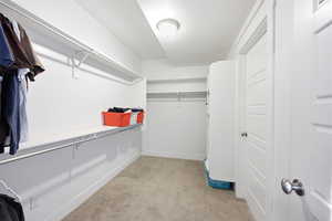Walk in closet featuring light colored carpet