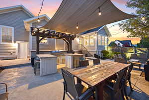 View of patio / terrace with an outdoor kitchen, a pergola, and an outdoor bar and dining area