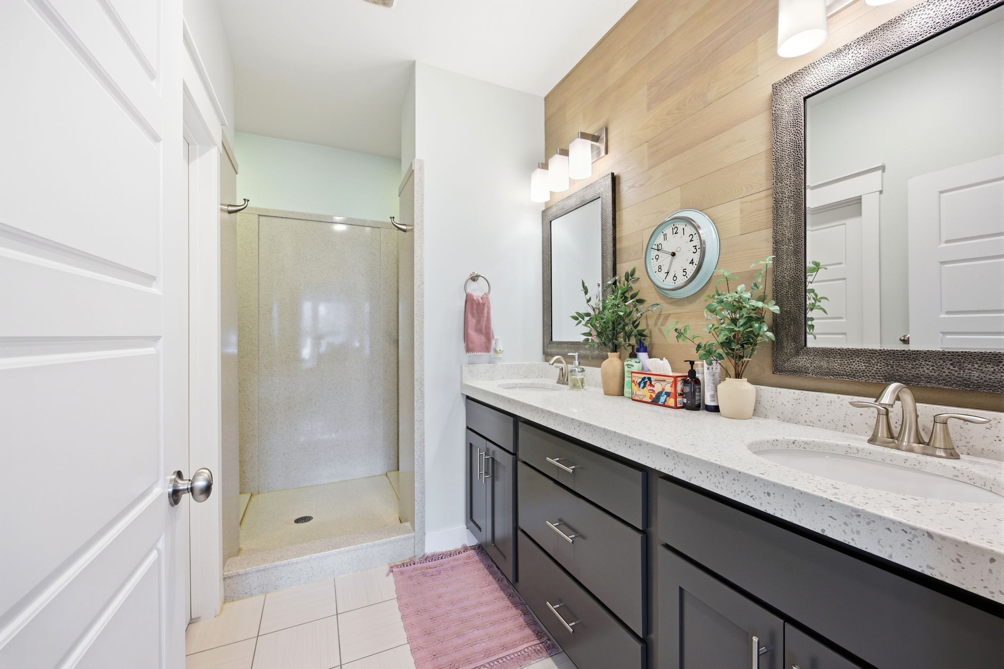 Bathroom featuring a stall shower, double vanity, and light tile patterned floors