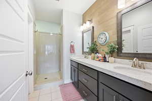 Bathroom featuring a stall shower, double vanity, and light tile patterned floors