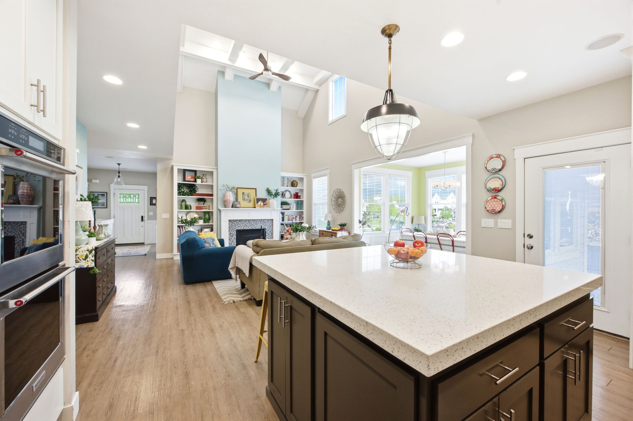 Kitchen with a fireplace, a center island, light stone counters, dark wood finish cabinetry, and double oven