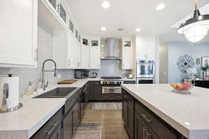 Two tone kitchen with light stone countertops, light wood-style floors, glass insert cabinets, decorative backsplash, and two tone cabinetry