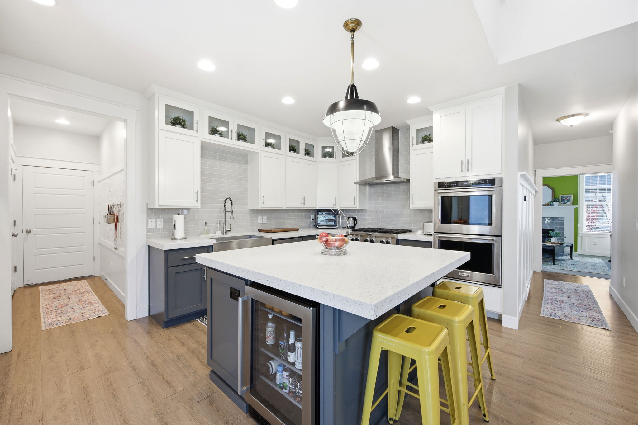 Kitchen with dual tone cabinets, glass insert cabinets, a kitchen island, light stone counters, and stainless steel appliances