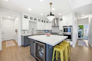 Kitchen with dual tone cabinets, glass insert cabinets, a kitchen island, light stone counters, and stainless steel appliances