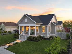 View of front of house featuring covered porch, a lawn, and a shingled roof