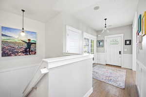 Foyer entrance featuring a wainscoted wall, a decorative wall, and light wood-style flooring