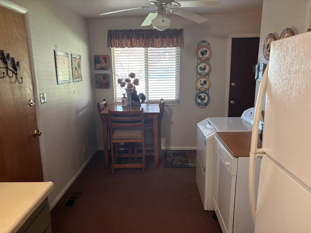 Laundry area with a ceiling fan, dark carpet, and washing machine and dryer