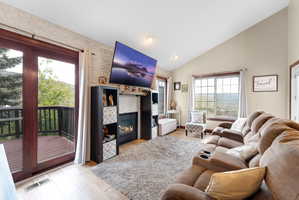 Living room with lofted ceiling, light wood-type flooring, and a fireplace