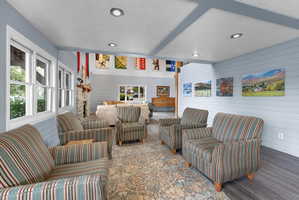 Living area with wood finished floors, a textured ceiling, wooden walls, beamed ceiling, and recessed lighting