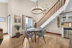 Dining room with a high ceiling, light wood finished floors, and a chandelier
