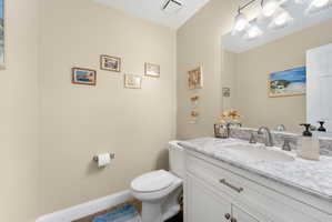 Half bath featuring vanity and baseboards, located next to garage entrance