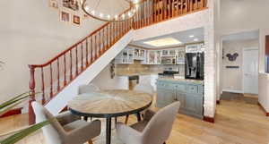 Dining space with hanging lights, light wood-style flooring, and a high ceiling
