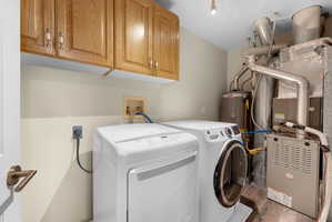 Laundry room with washer and dryer, cabinet space, and heating unit