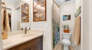 Full bath with curtained shower, vanity, light tile patterned floors, and a spacious closet
