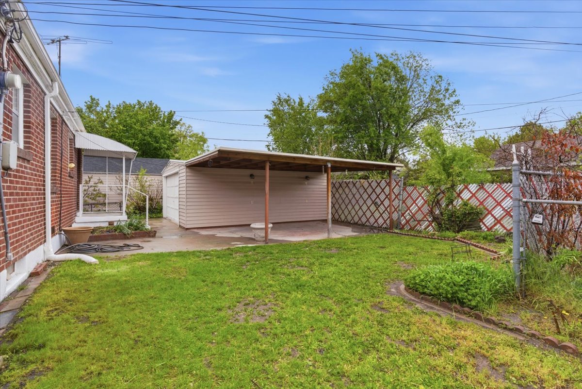 Fenced yard with an outdoor structure and a patio area