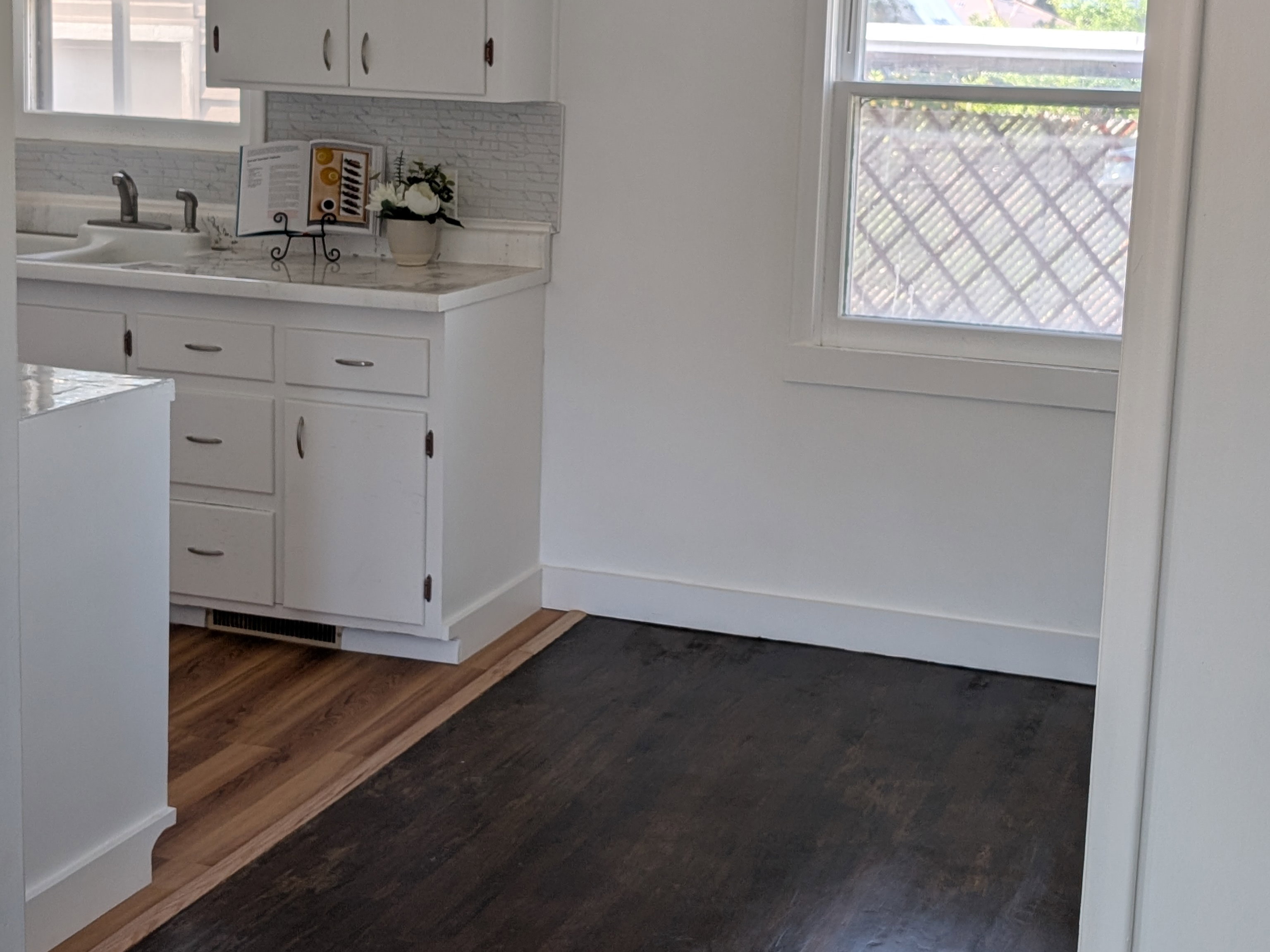 Kitchen with light countertops, dark wood-type flooring, tasteful backsplash, and plenty of natural light