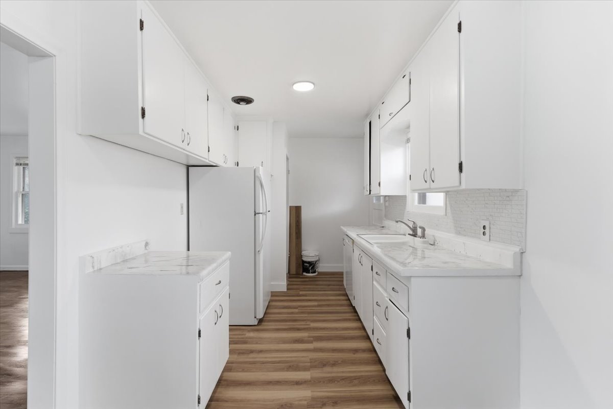 Kitchen featuring light countertops, freestanding refrigerator, light wood-style flooring, white cabinetry, and recessed lighting