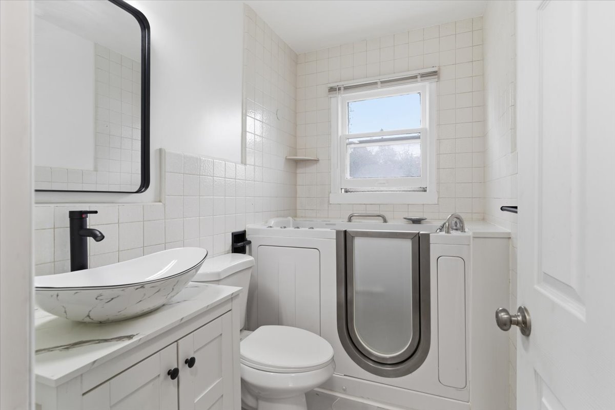 Full bath featuring tile walls, vanity, and a garden tub