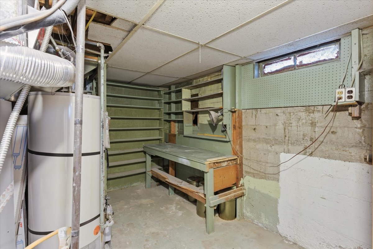 Unfinished below grade area with water heater and a paneled ceiling