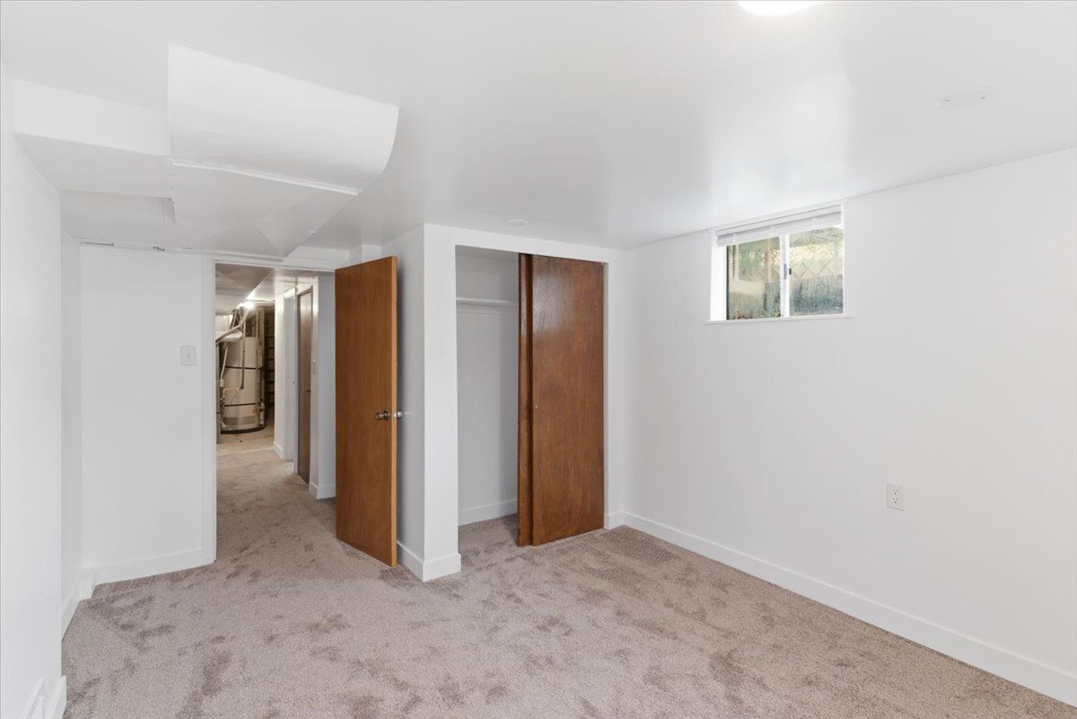 Unfurnished bedroom with light colored carpet, a closet, and water heater
