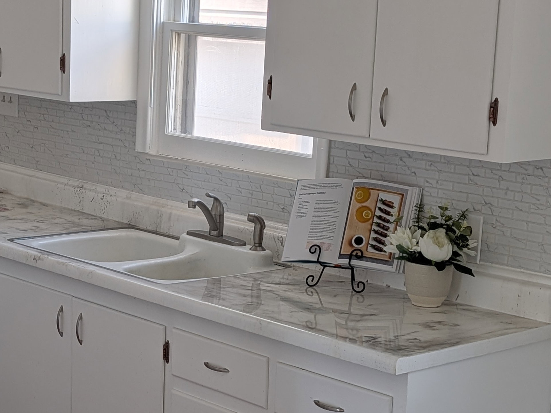 Kitchen featuring dark wood-style floors, light countertops, white cabinetry, decorative backsplash, and white dishwasher