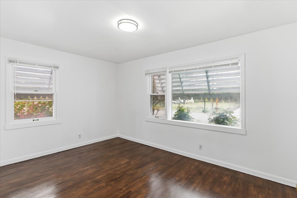 Unfurnished room with baseboards and dark wood-style flooring