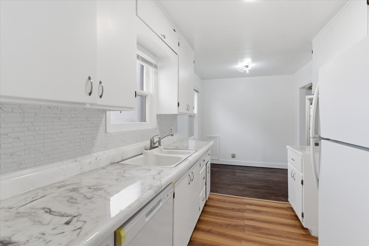 Kitchen featuring white appliances, dark wood-style floors, white cabinetry, and light countertops