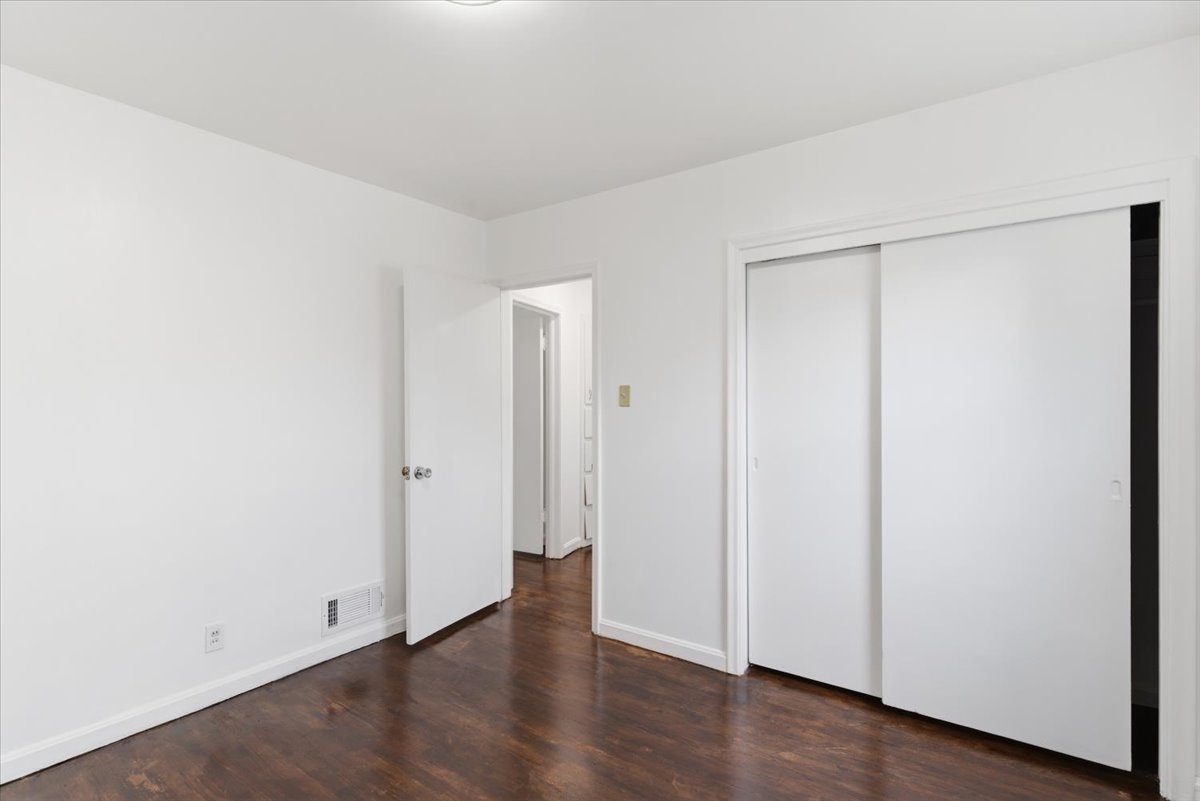 Unfurnished bedroom featuring dark wood finished floors and a closet