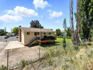 Back of property with a deck, a chimney, and a yard