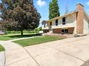 Bi-level home with a front lawn, brick siding, and a chimney
