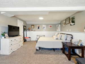 Bedroom with a wainscoted wall, light colored carpet, and a textured ceiling