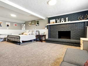 Bedroom with carpet floors, wainscoting, a brick fireplace, and a textured ceiling
