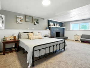 Bedroom with a textured ceiling, carpet, a fireplace, and a wainscoted wall