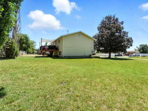 View of side of property featuring a yard and a wooden deck