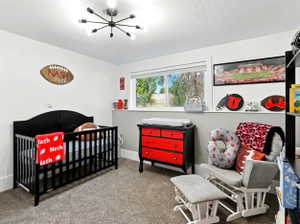 Bedroom featuring a crib, a textured ceiling, and carpet